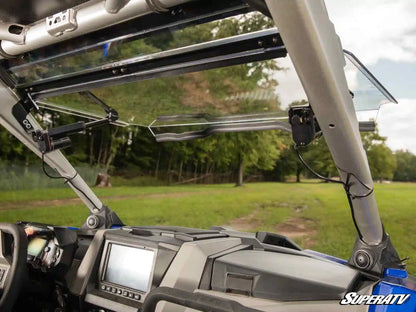 Close-up of a SuperATV windshield on an off-road vehicle with a grassy field background.