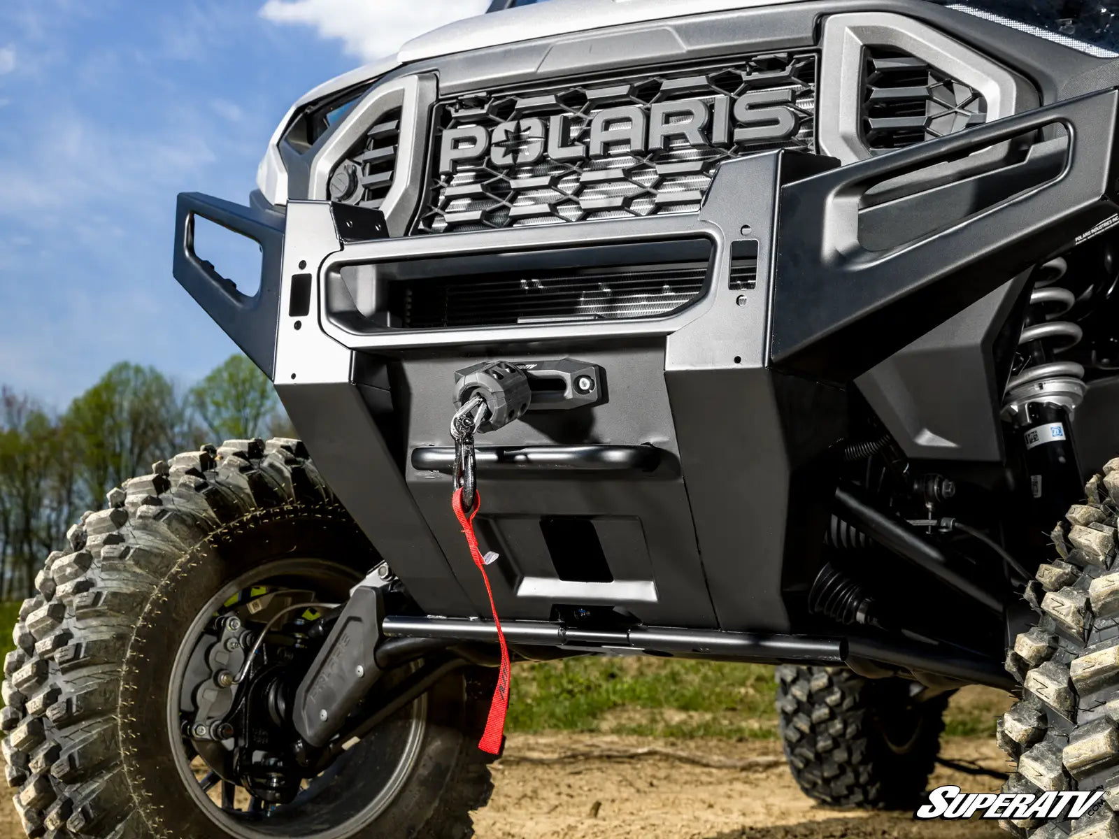 Close-up of a Polaris vehicle with a SuperATV logo on a clear day.