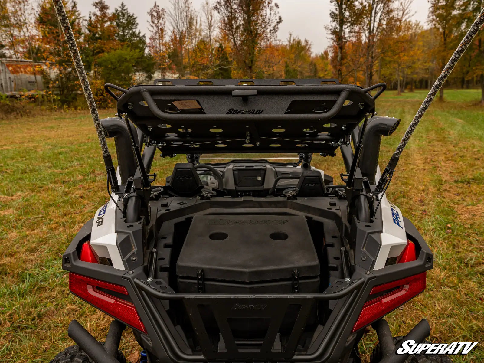 Back view of a SuperATV vehicle with open cargo area on grassy field