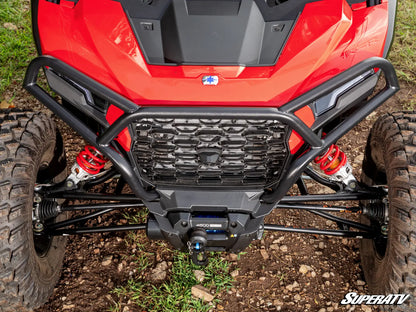 Close-up of a red ATV with a black front bumper on a grassy and rocky terrain.