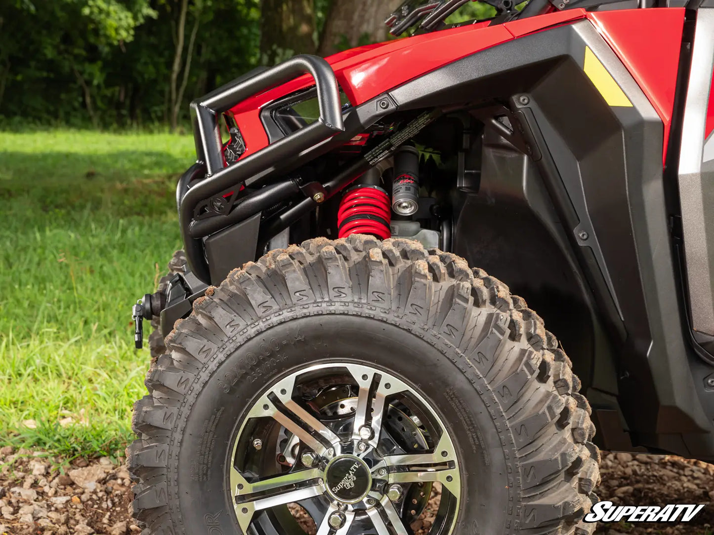 Close-up of a red ATV with off-road tire and suspension system on a natural background.