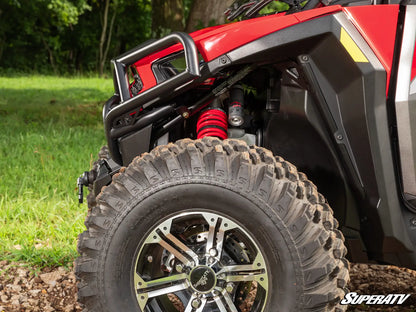 Close-up of a red ATV with off-road tire and suspension system on a natural background.