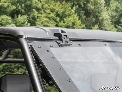Close-up of a vehicle roof rack system with SuperATV branding against a blurred green background.