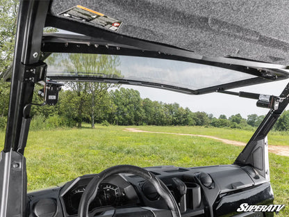 Interior of a SuperATV vehicle with open roof showing a grassy field and trees outside.
