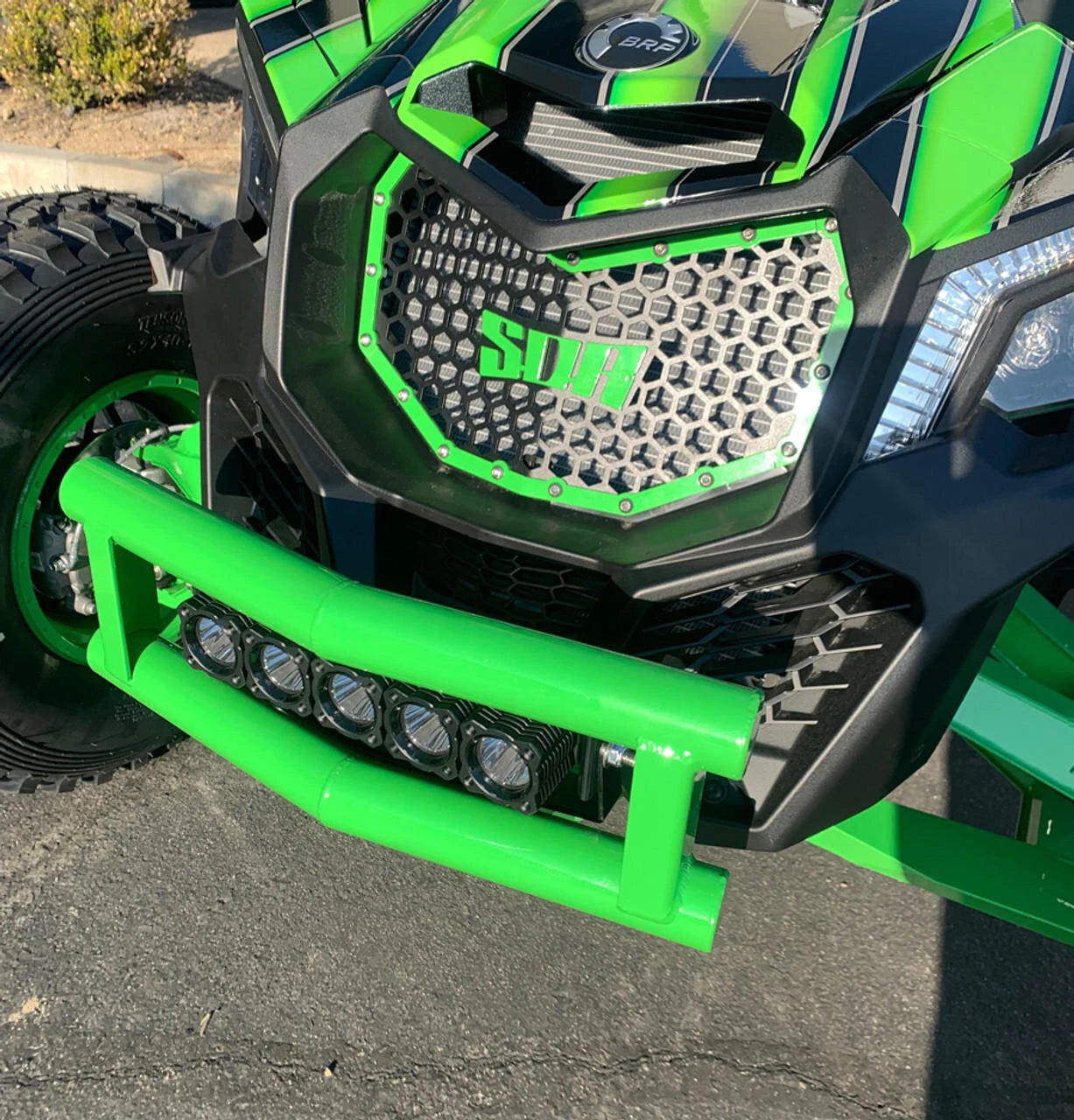 Close-up of a green and black off-road vehicle with visible branding on a paved surface.