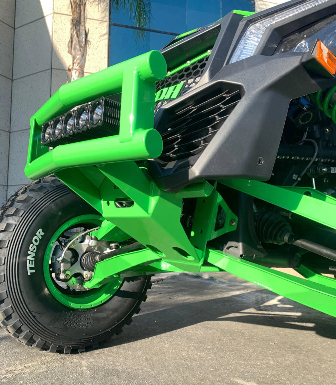 Close-up of a green off-road vehicle with large tires and visible Tensor branding.