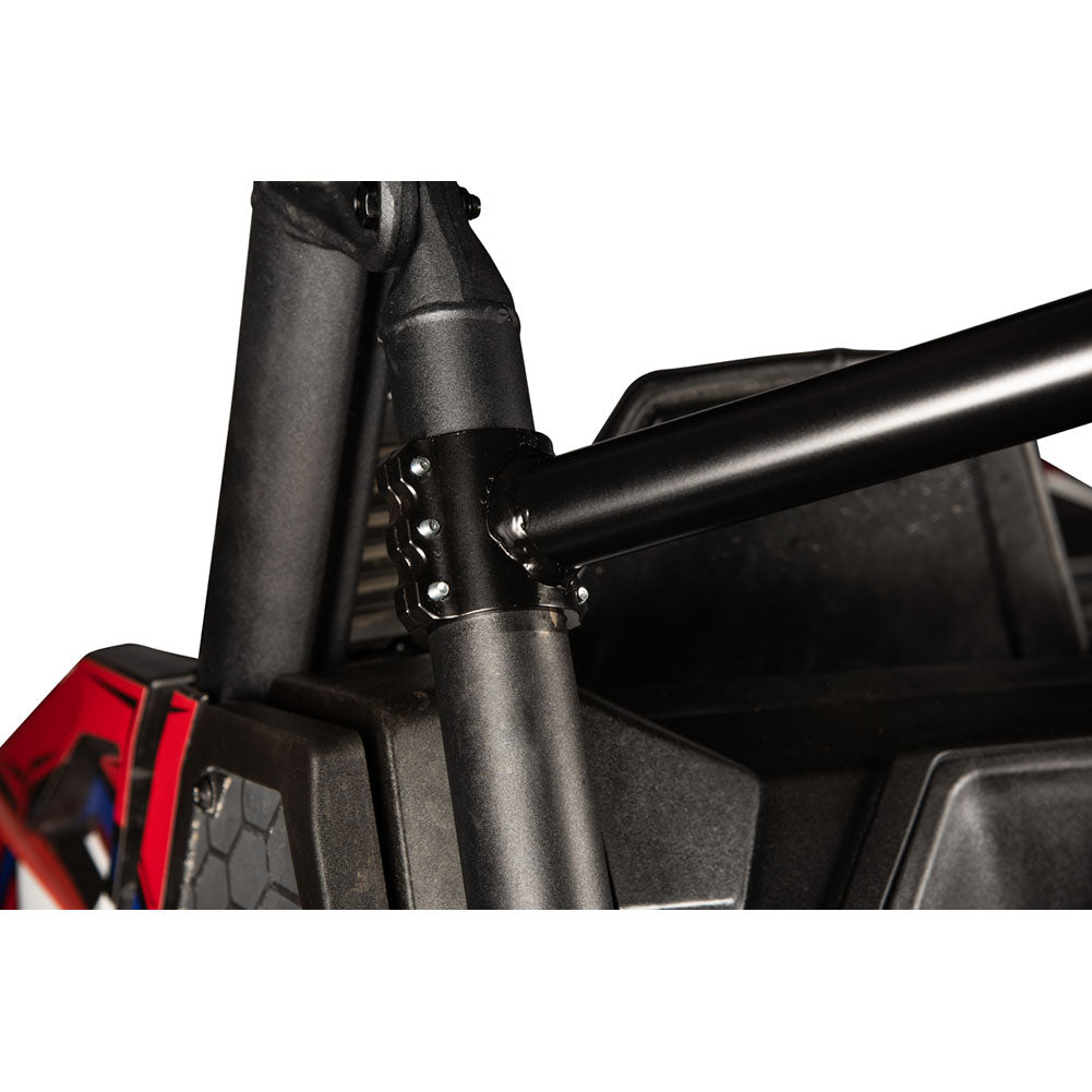 Close-up of a black metal roll bar mounting bracket attached to a tubular frame on a vehicle, with a red and black body panel visible on the left against a white background.