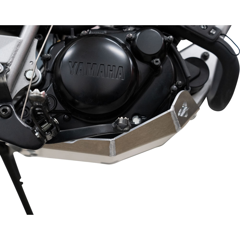 A close-up of a motorcycle engine cover with a black Yamaha logo and a silver metal engine guard below it, shown against a white background.