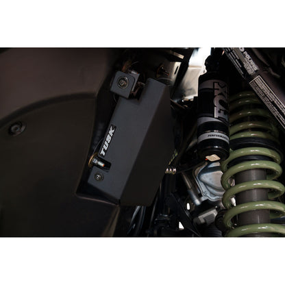 Close-up of a suspension system with a shock absorber and Tusk brand logo.