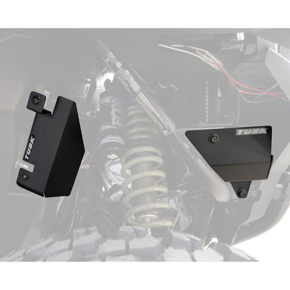 Two black metal brackets on a vehicle suspension system with 'Tusk' branding.