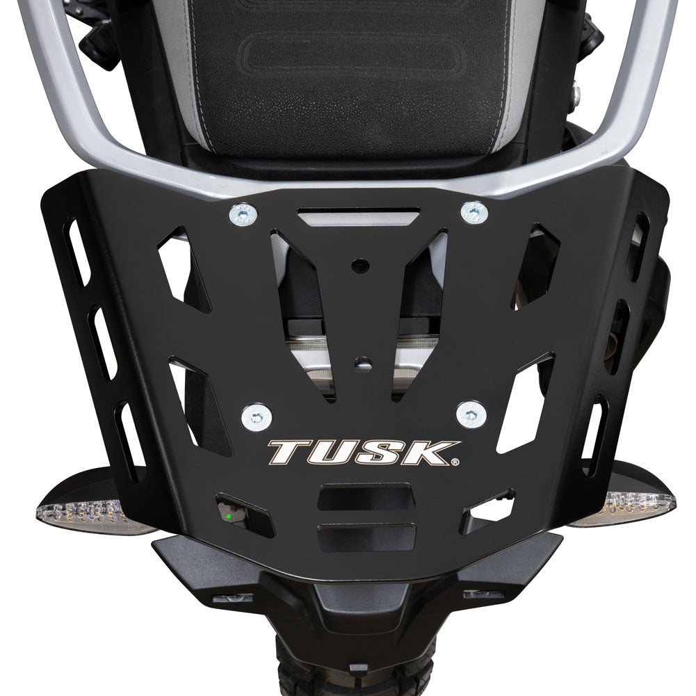 A close-up of a black metal TUSK motorcycle front bumper guard with silver hardware, shown mounted on a motorcycle against a white background.