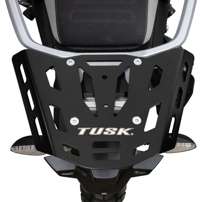A close-up of a black metal TUSK motorcycle front bumper guard with silver hardware, shown mounted on a motorcycle against a white background.