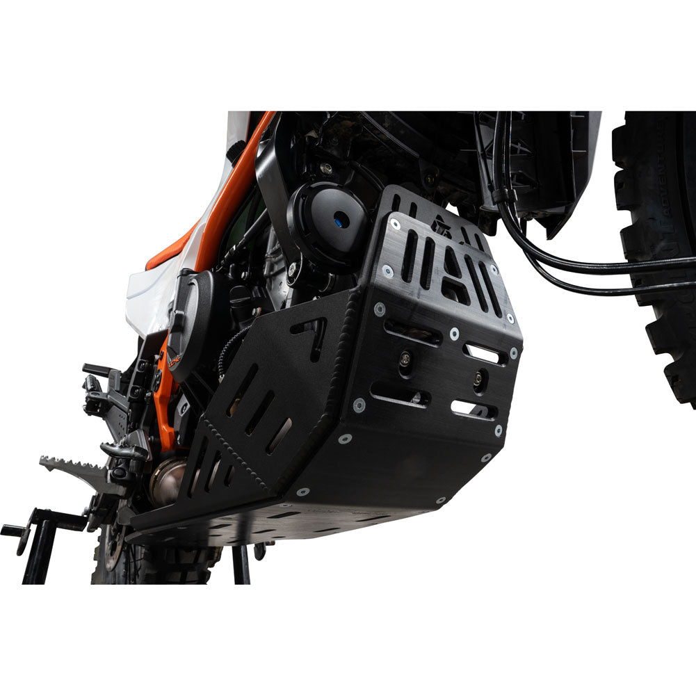 A black metal protective under-bench guard with pre-drilled mounting holes, shown installed on the frame of a motorcycle against a white background.