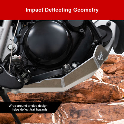 Close-up of a motorcycle ground clearance skid plate installed over a rocky trail setting, with text overlays reading 'Impact Deflecting Geometry' and 'Wrap-around angled design helps deflect trail hazards.'.