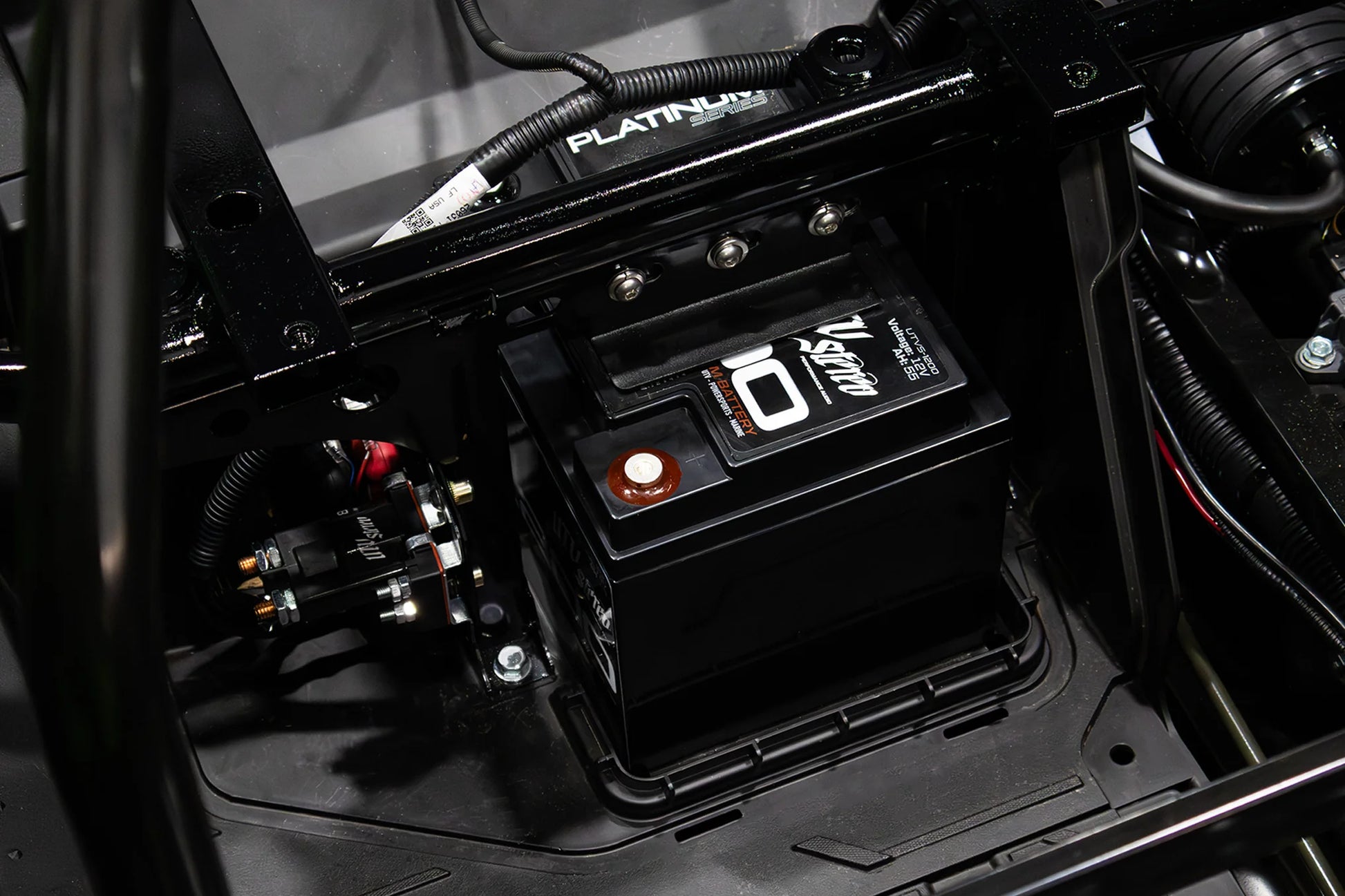 Close-up of a battery in a vehicle's engine compartment with visible branding.